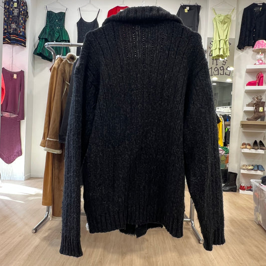 Black cardigan on a rack in a clothing store with various garments in the background