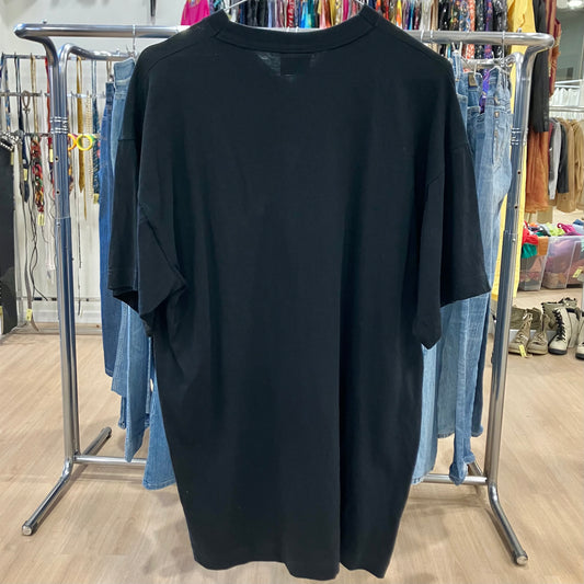 Black dress on a hanger in a store setting with jeans and other clothing in the background