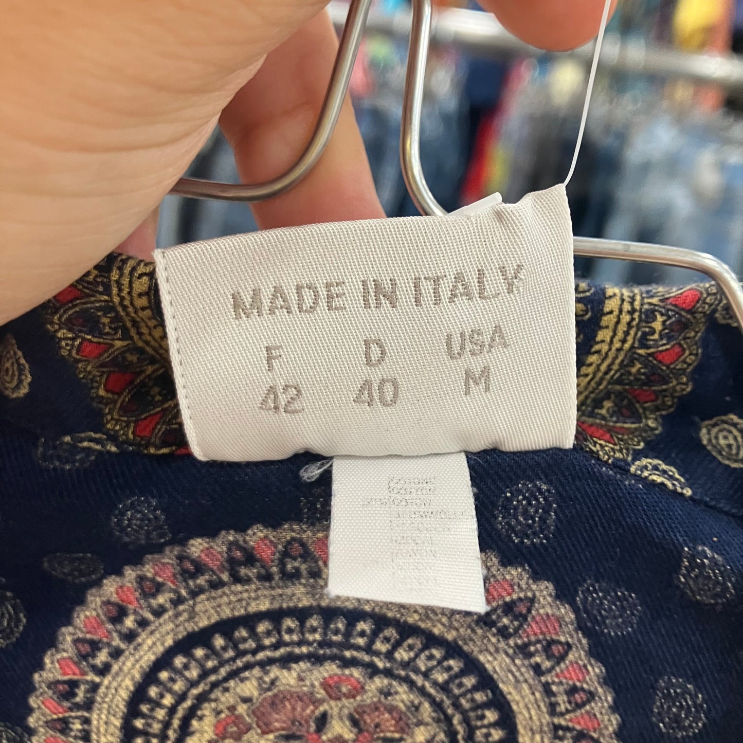 Clothing tag with 'Made in Italy' text on a patterned fabric background