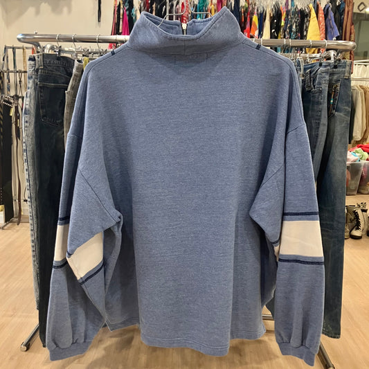 Blue sweater on a rack with clothing in the background