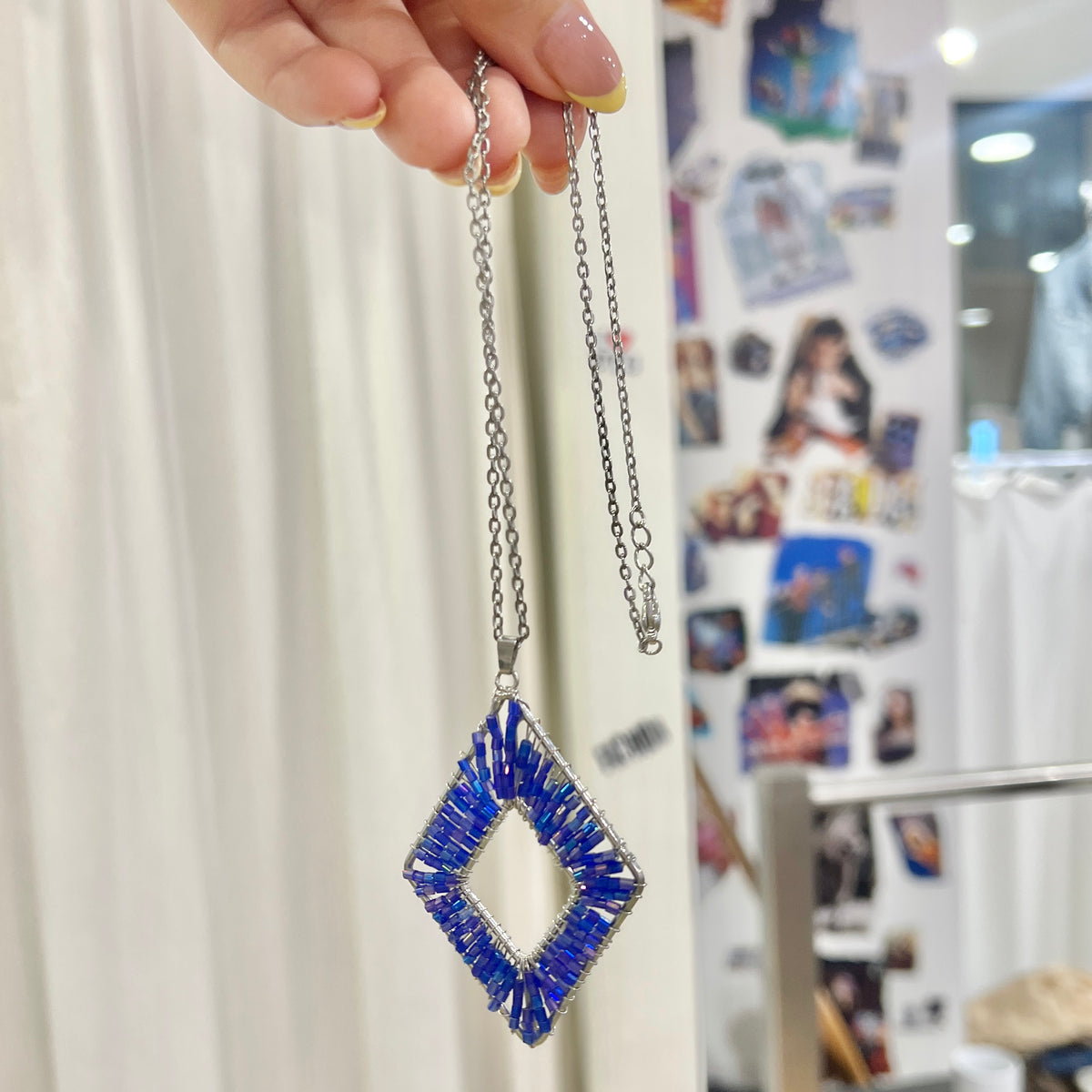 silver chain necklace with diamond shaped blue beaded pendant