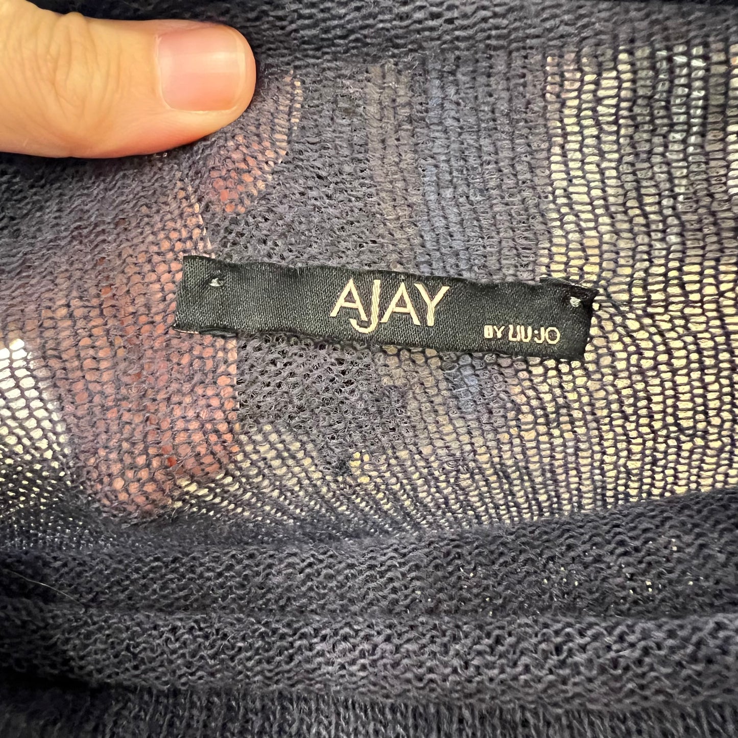 Close-up of a 'AJAY by Liu Ju' label on textured fabric