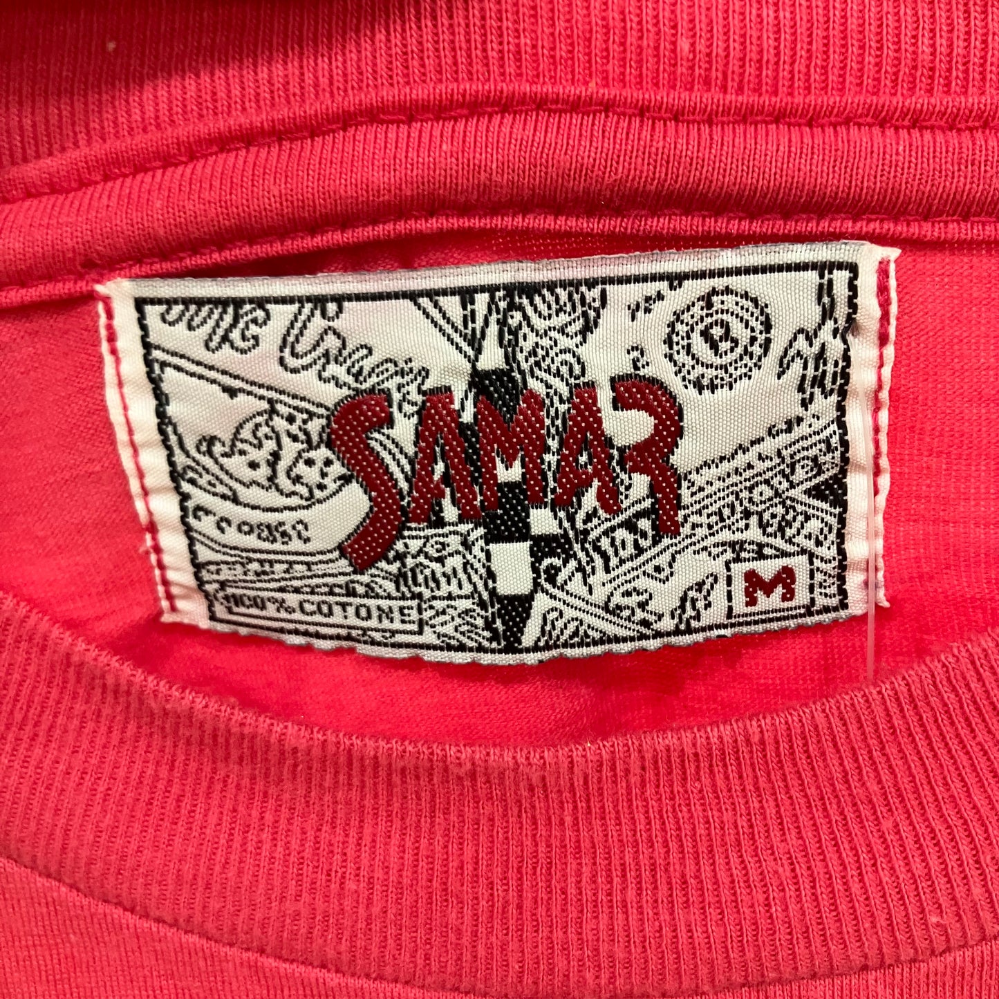 Close-up of a red sweatshirt with a brand label on a red background