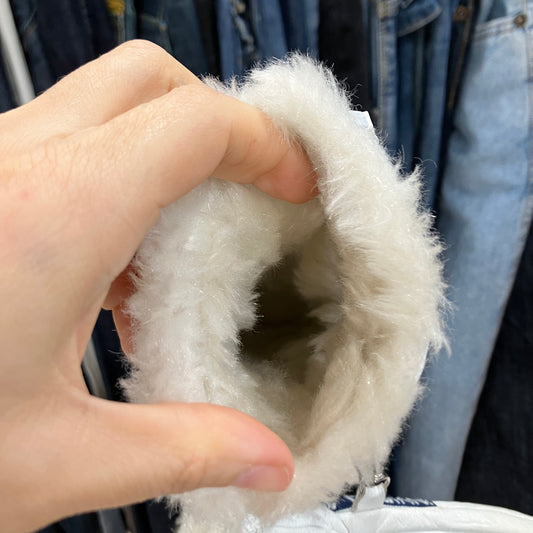 Close-up of a hand holding a white furry item against a blurred background