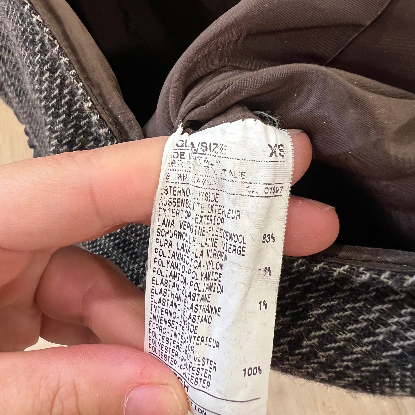 Close-up of a fabric tag on a piece of clothing with text and measurements.