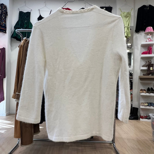 White sweater on a rack in a clothing store with various garments in the background
