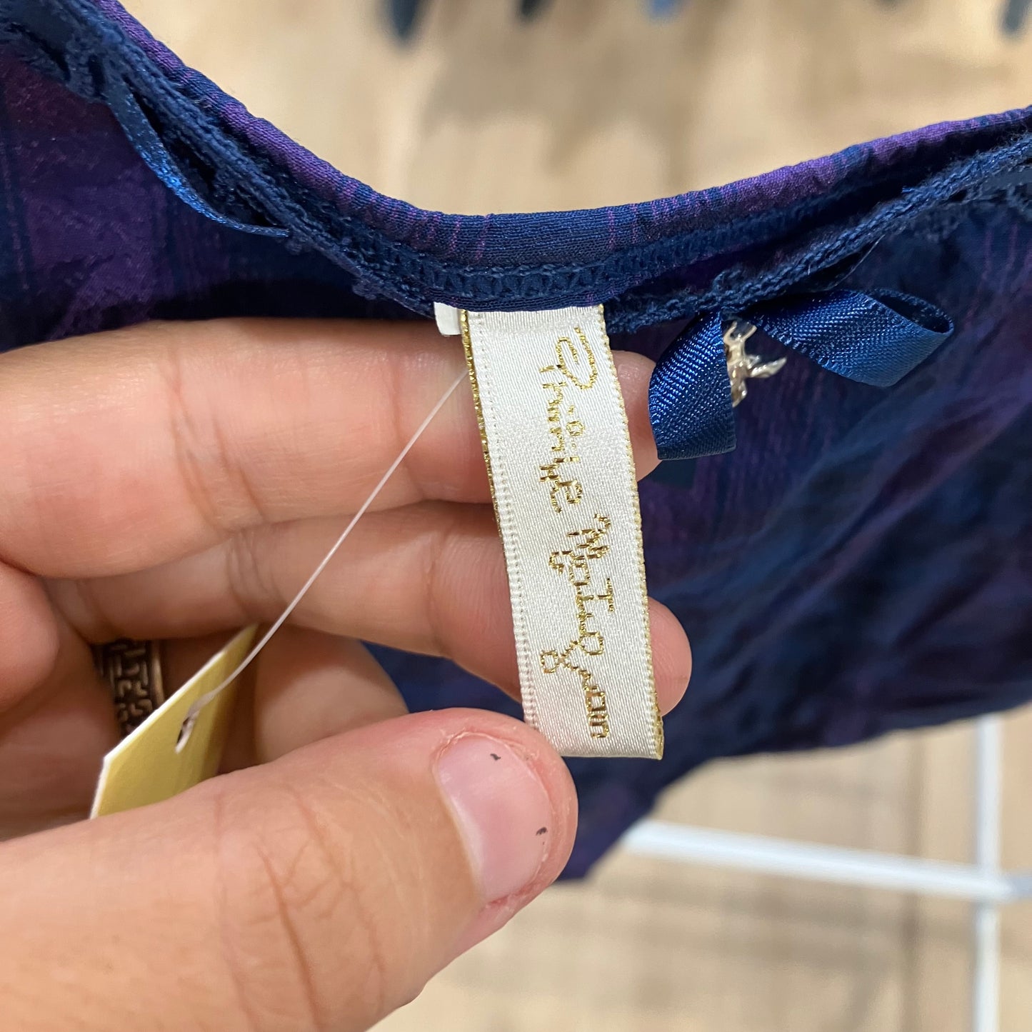 Close-up of a hand holding a clothing tag with text on a blurred background