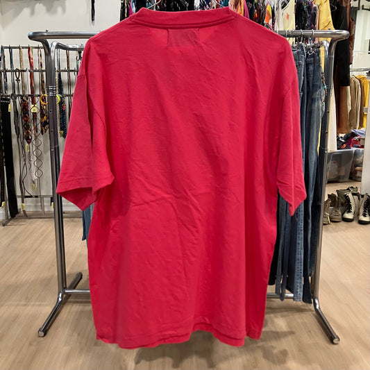 Red shirt on a rack in a store setting with various items in the background
