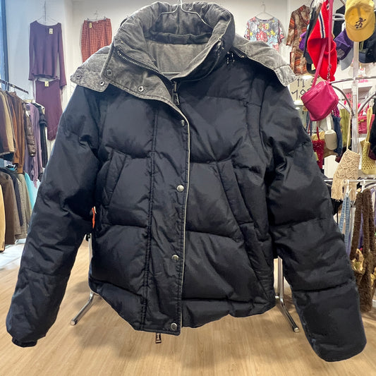 Black puffer jacket on a hanger in a store setting with clothing racks in the background