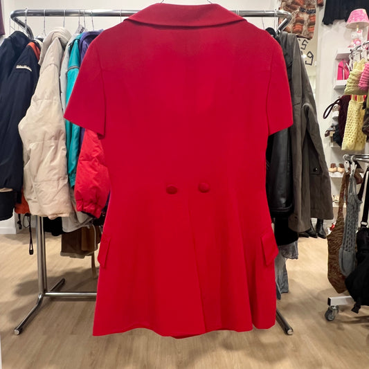 Red coat displayed in a clothing store with racks of other coats in the background