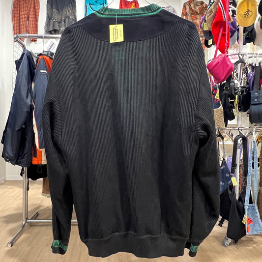 Black ribbed sweater on a rack with a colorful background of clothing
