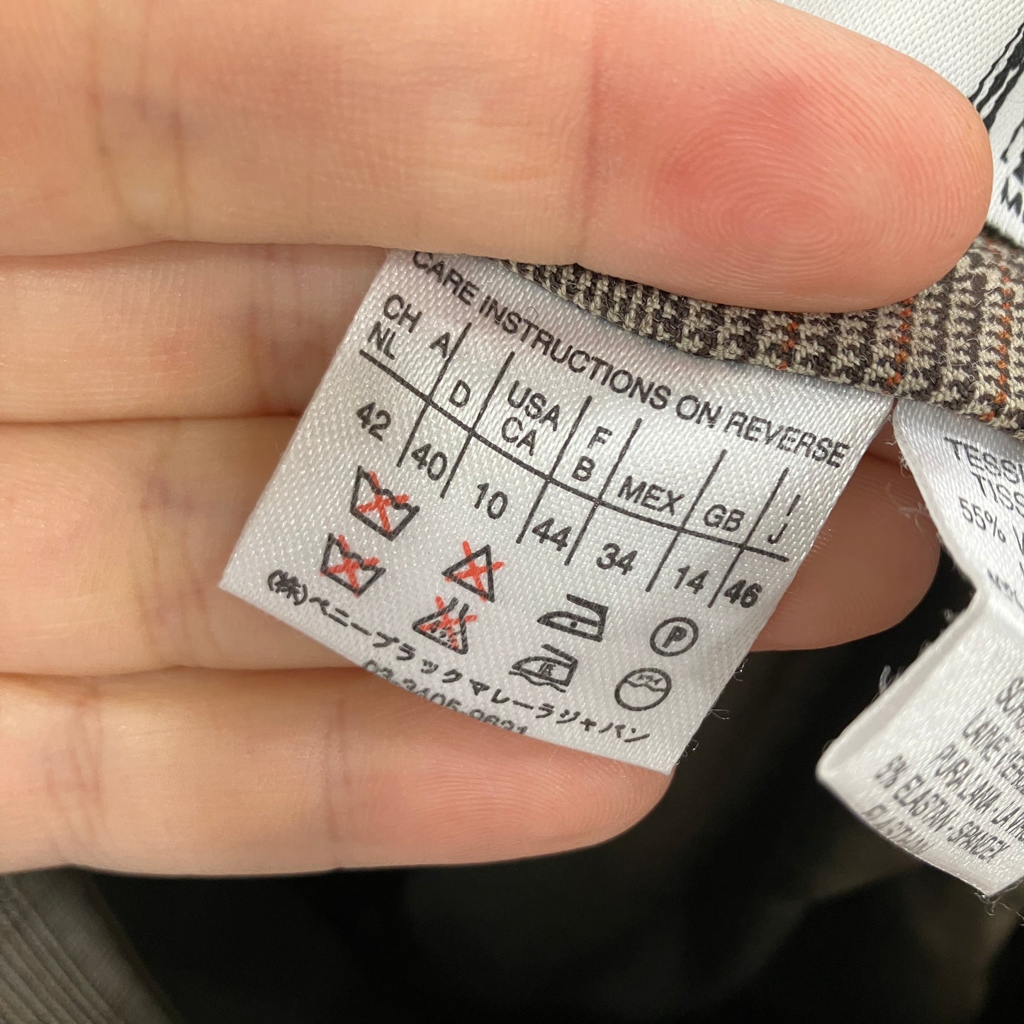 Clothing label with care instructions held by a hand