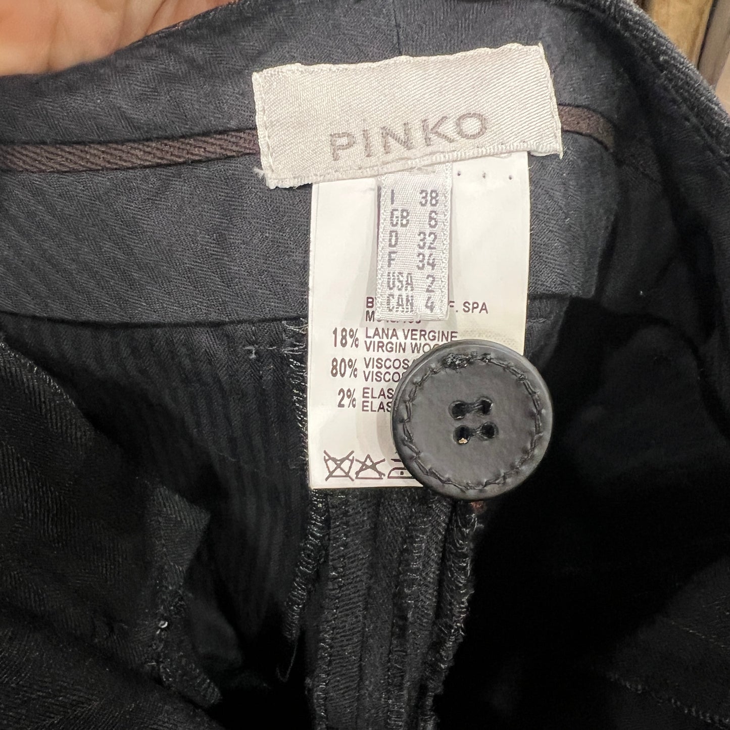 Close-up of a Pinko label on a garment with a button