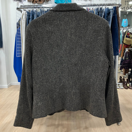 Gray jacket on a hanger in a store setting with clothing racks in the background