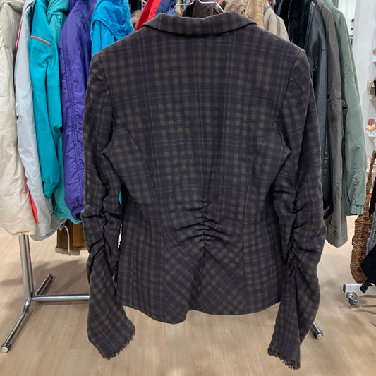 Dark plaid jacket on a hanger with a clothing rack in the background