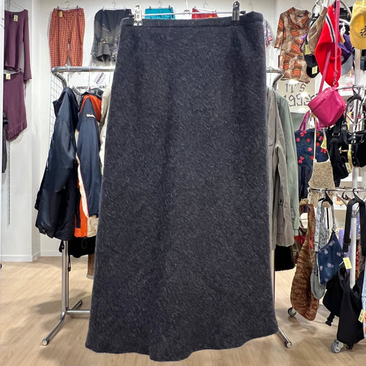 Dark gray skirt on a hanger in a clothing store with various garments in the background