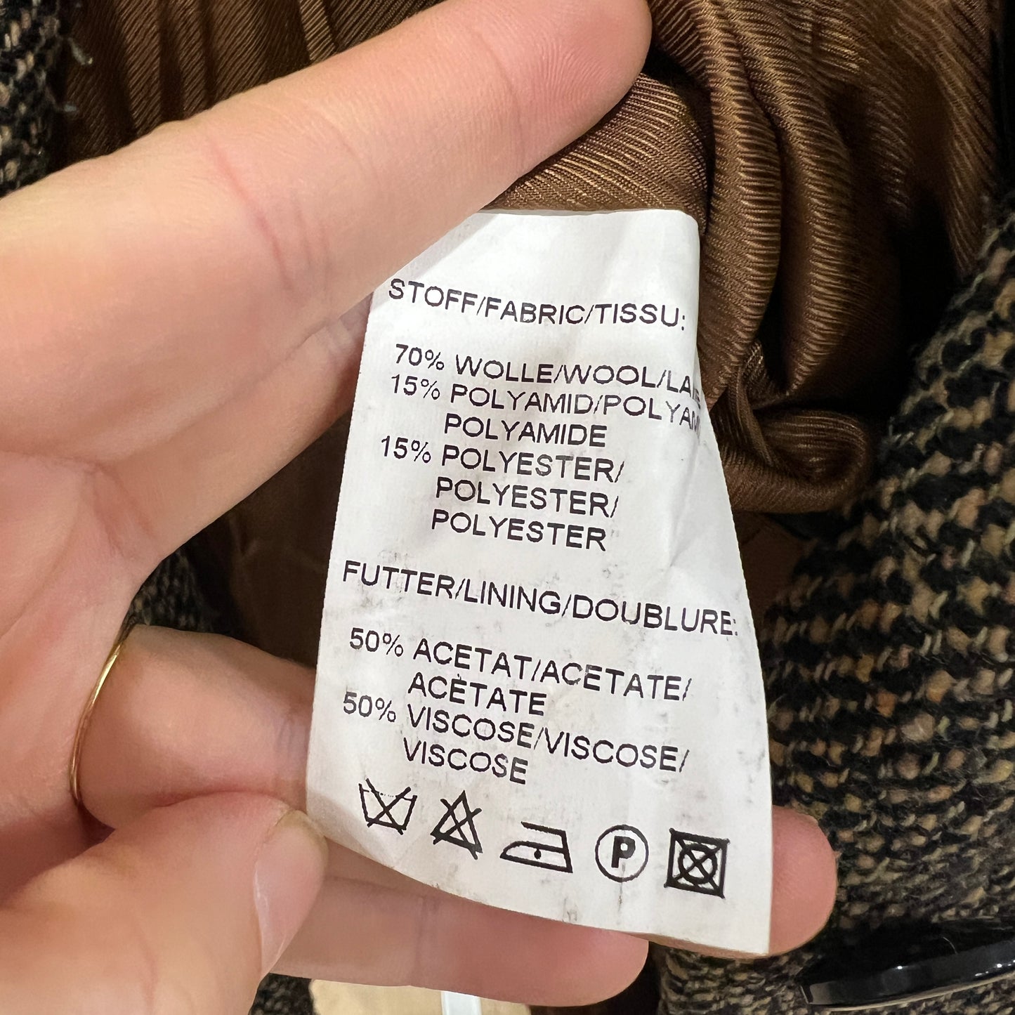Fabric label held by a hand with clothing background