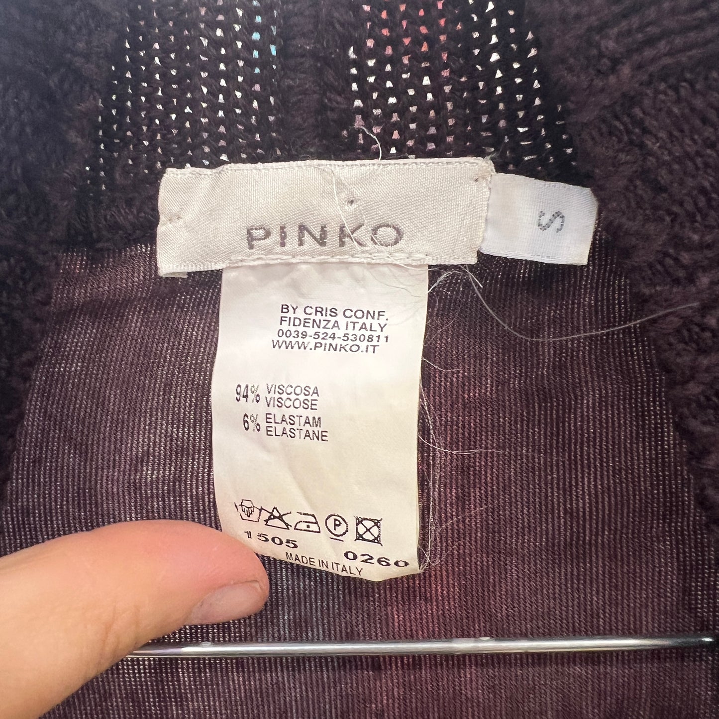 Pinko label on a garment with a hand pointing to it