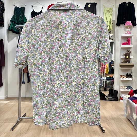 Floral patterned shirt on a hanger in a store setting with clothing racks and shelves in the background