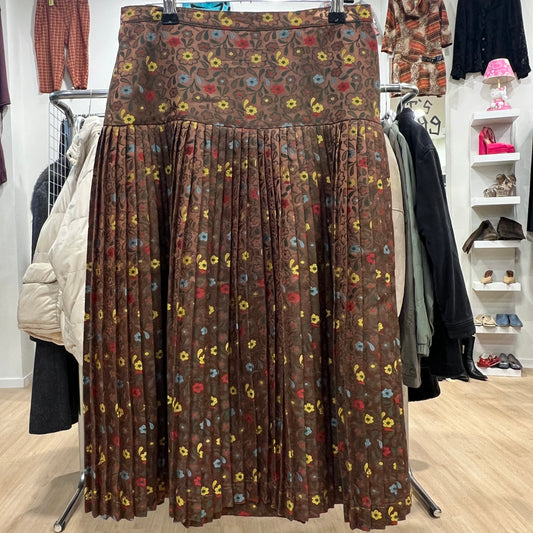 Brown floral-patterned skirt displayed in a store setting with clothing racks and shelves in the background