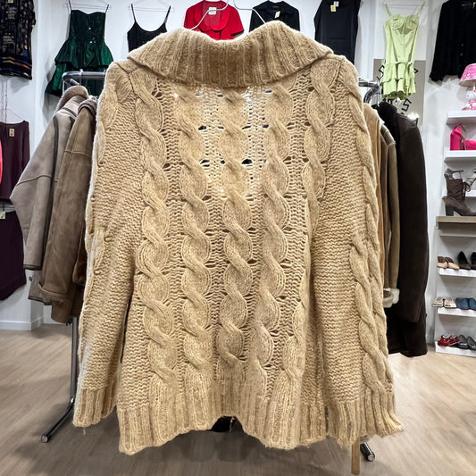 Beige cable knit sweater on a mannequin in a clothing store setting