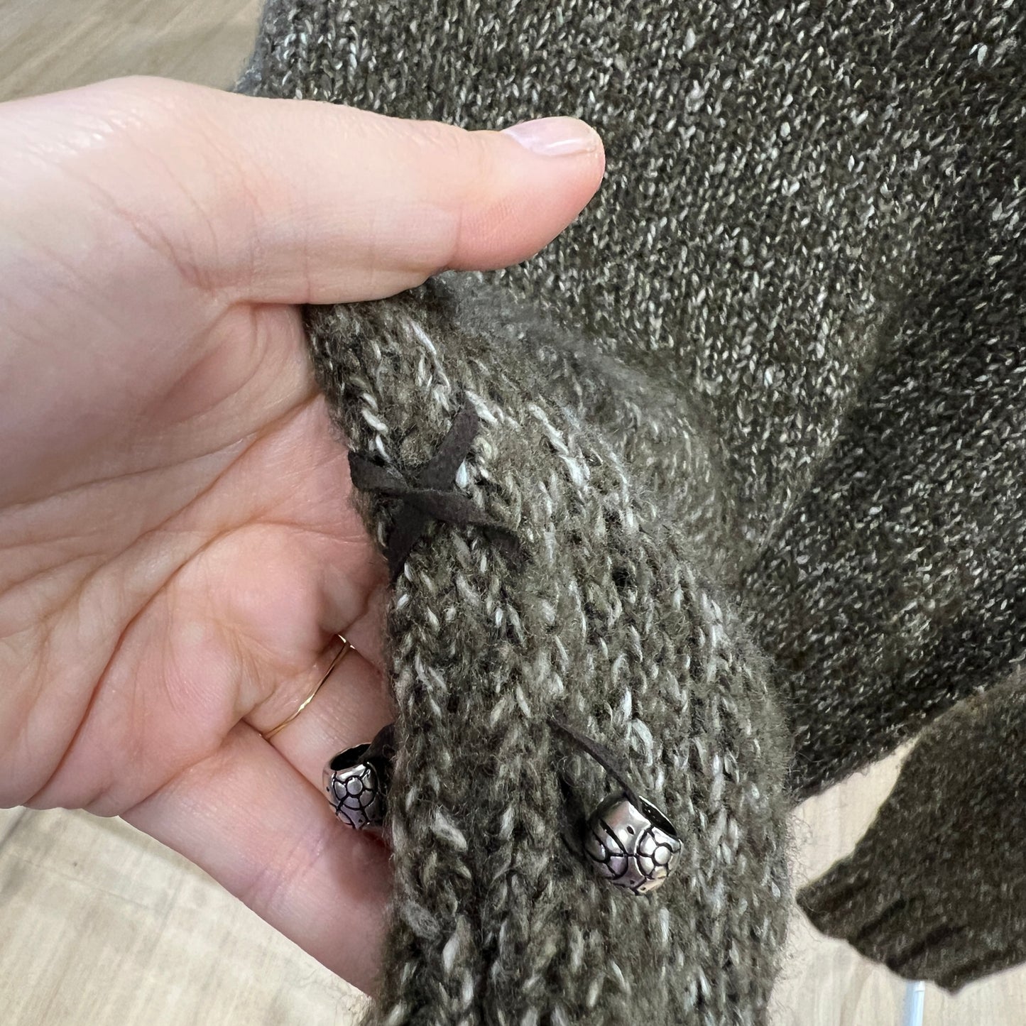 Close-up of a hand holding a textured fabric with metal buttons
