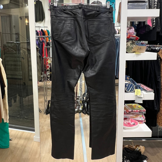 Black leather pants displayed in a store setting with clothing racks and shelves in the background