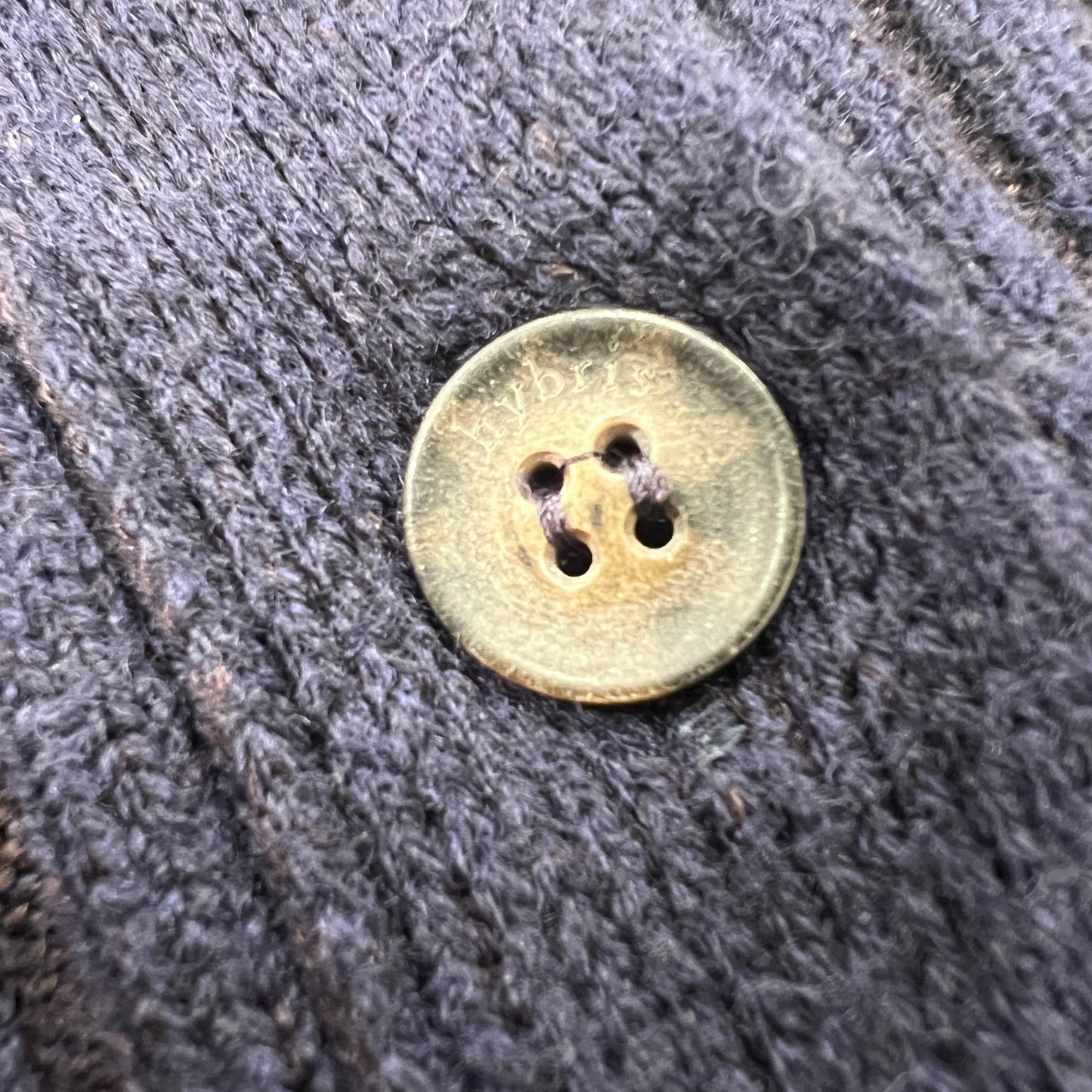 Round button with two holes on a textured gray fabric background