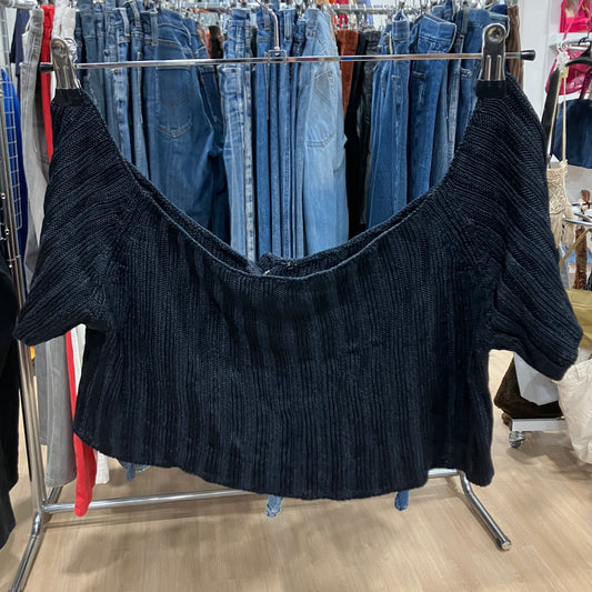 Black ribbed sweater on a rack with jeans in a store setting