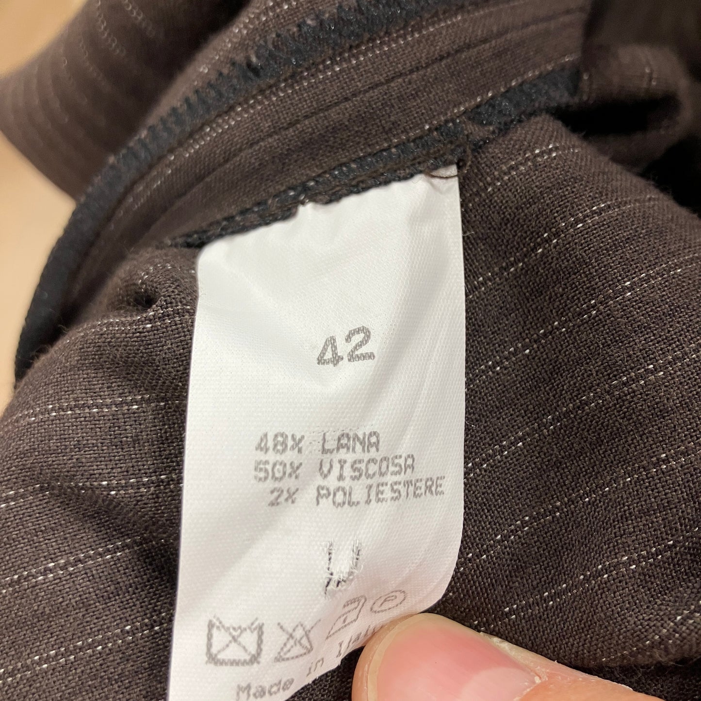 Close-up of a clothing label on a brown fabric garment with visible text