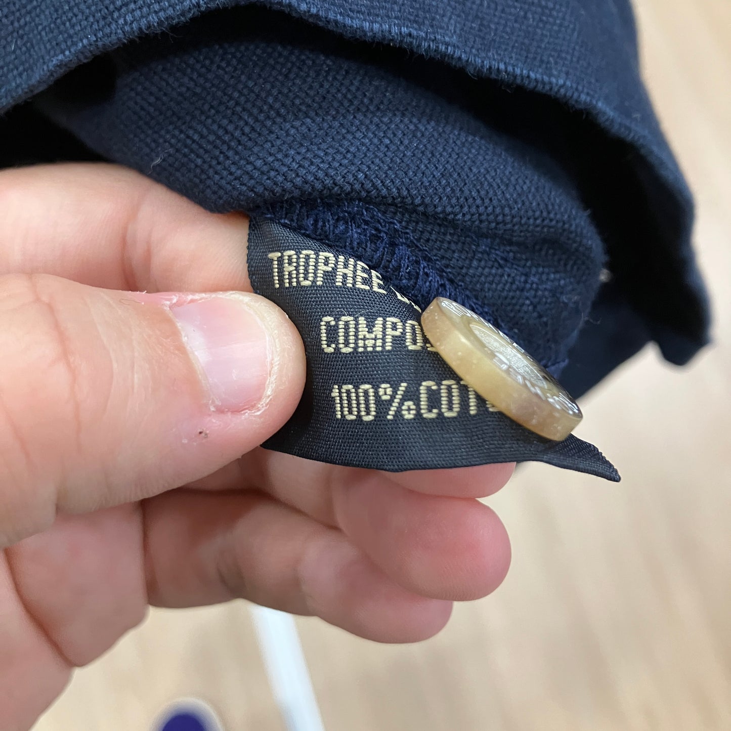 Hand holding a clothing label with text on a blurred background