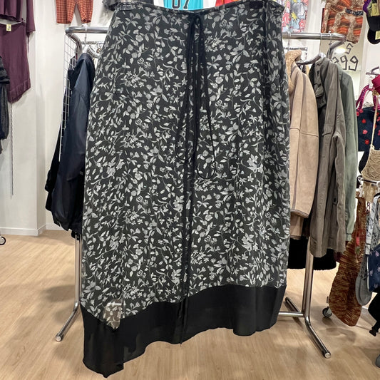 Black floral-patterned skirt on a clothing rack in a store setting