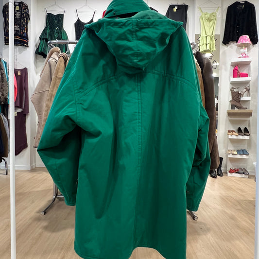 Green raincoat in a clothing store with racks of clothes and shoes in the background