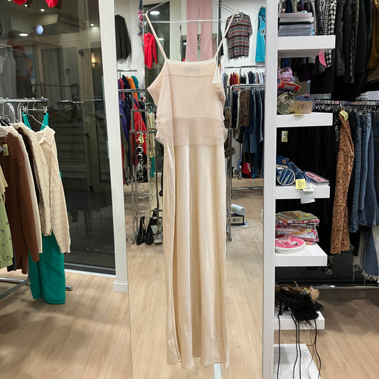 Beige dress hanging on a rack in a clothing store with various garments on shelves and racks