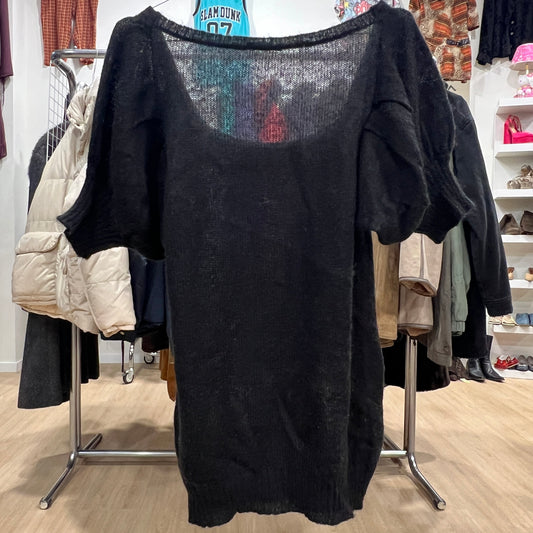 Black sweater with sheer back on a clothing rack in a store setting
