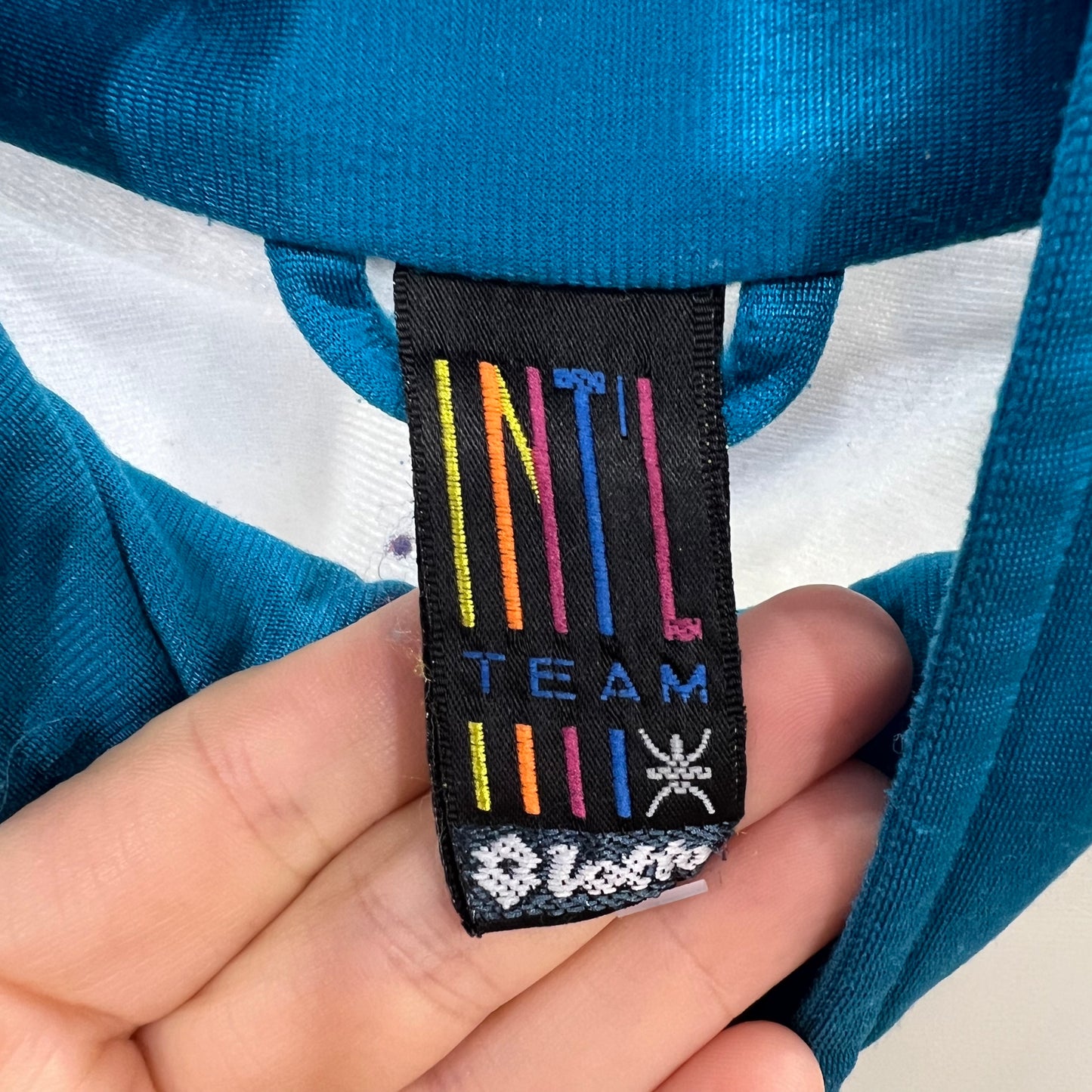 Close-up of a label on a blue and white striped track jacket held by a hand