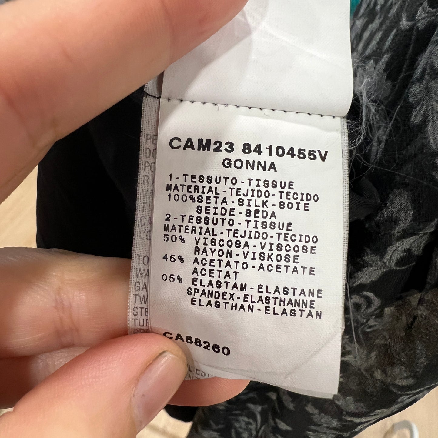 Close-up of a composition label inside a skirt, listing fabric details including 100% silk for the first fabric and a blend of viscose, acetate, and elastane for the second fabric