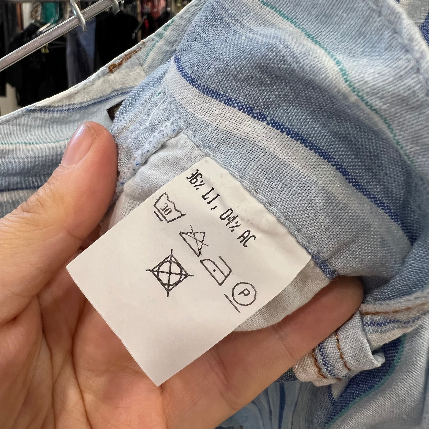 Clothing label held by a hand with a garment in the background