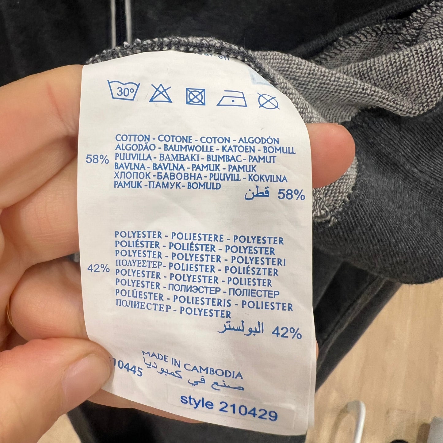 Clothing label with fabric composition details held by a hand