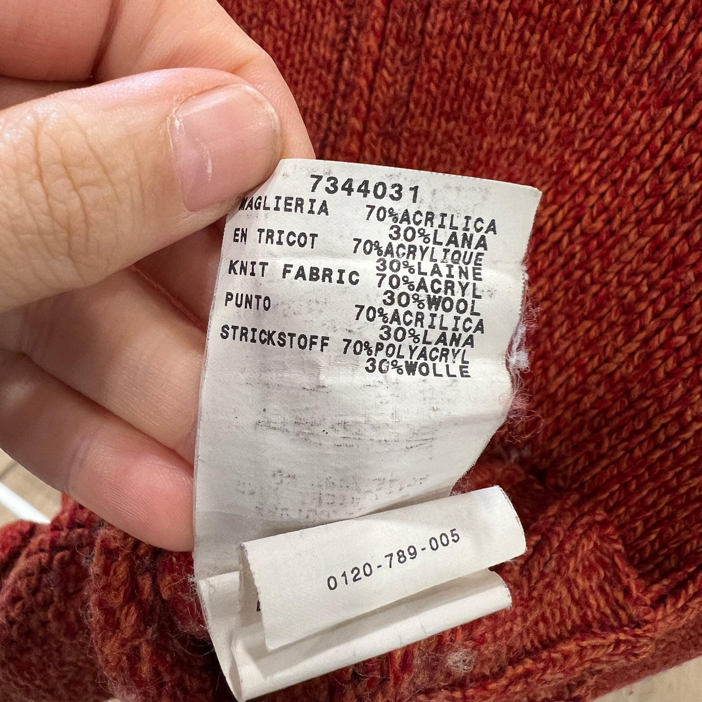 Close-up of a fabric label held over a knitted item with text on it