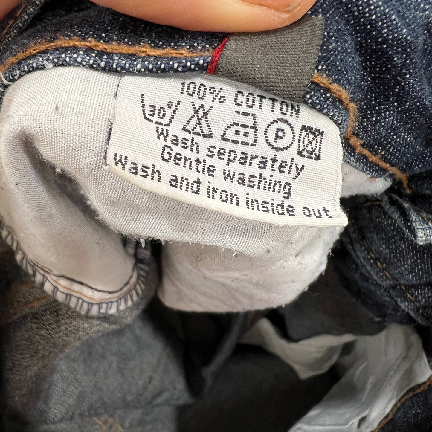 Close-up of a clothing label on denim fabric with washing instructions