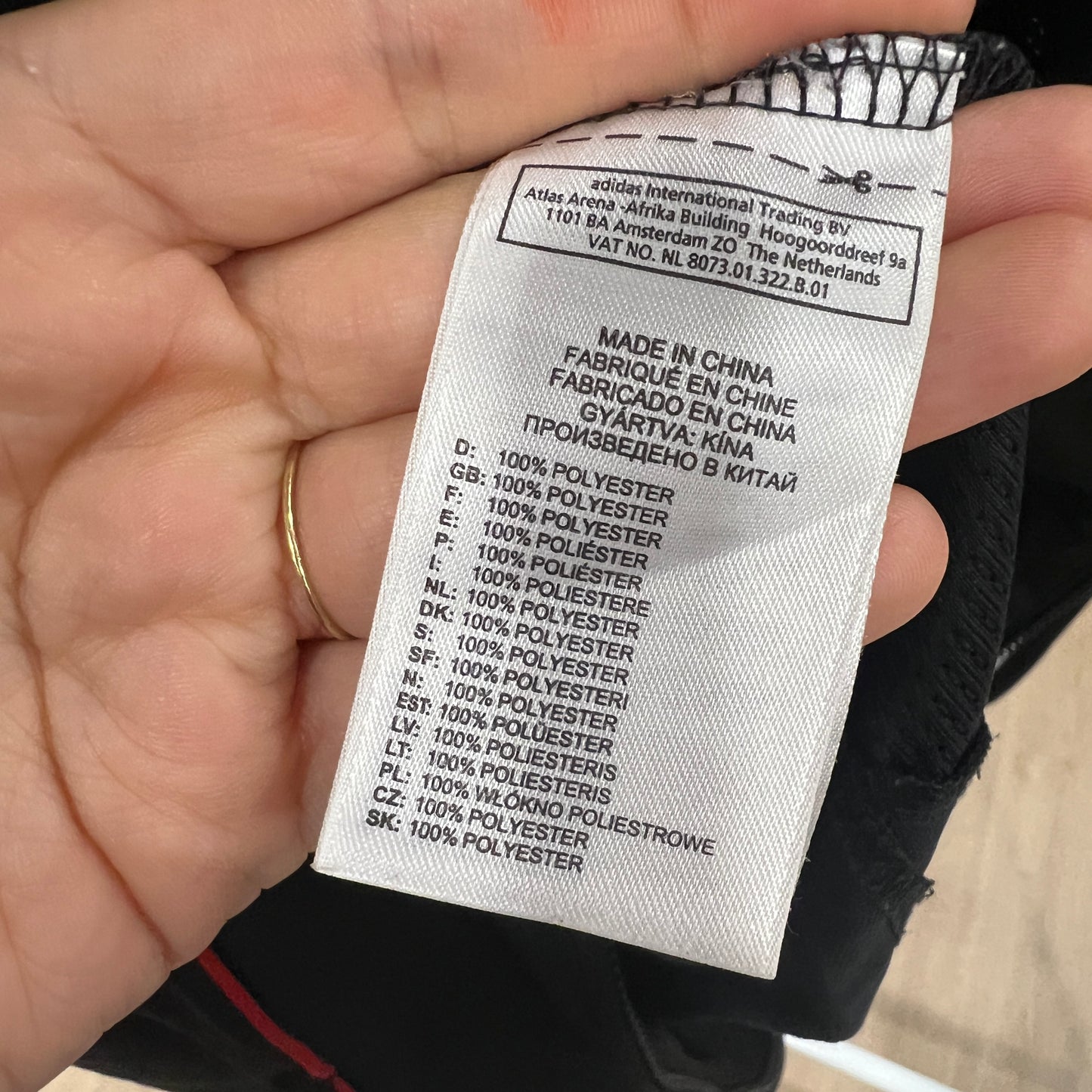 Clothing label held by a hand with text on it