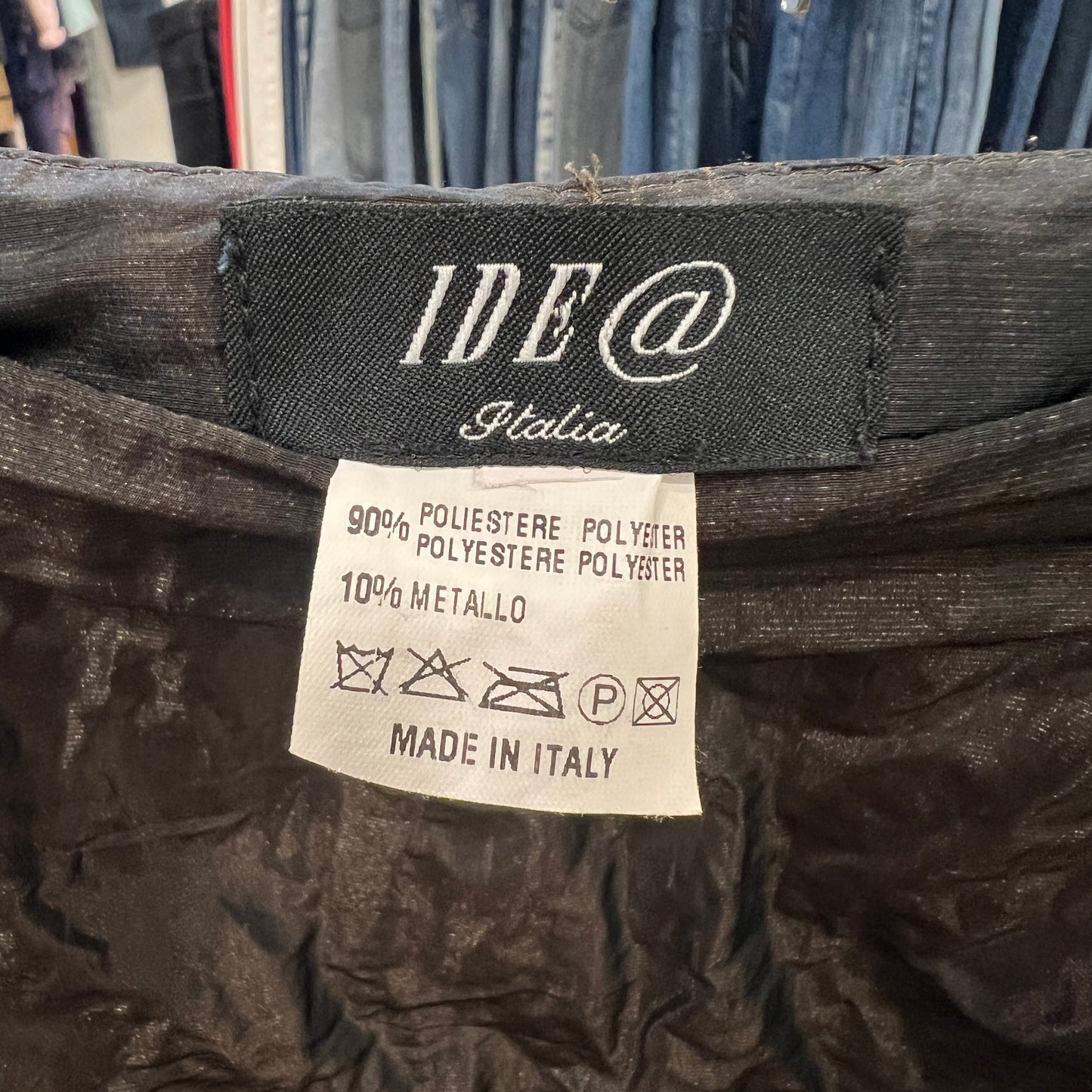 Clothing label with 'IDE @ Italia' on a dark fabric background