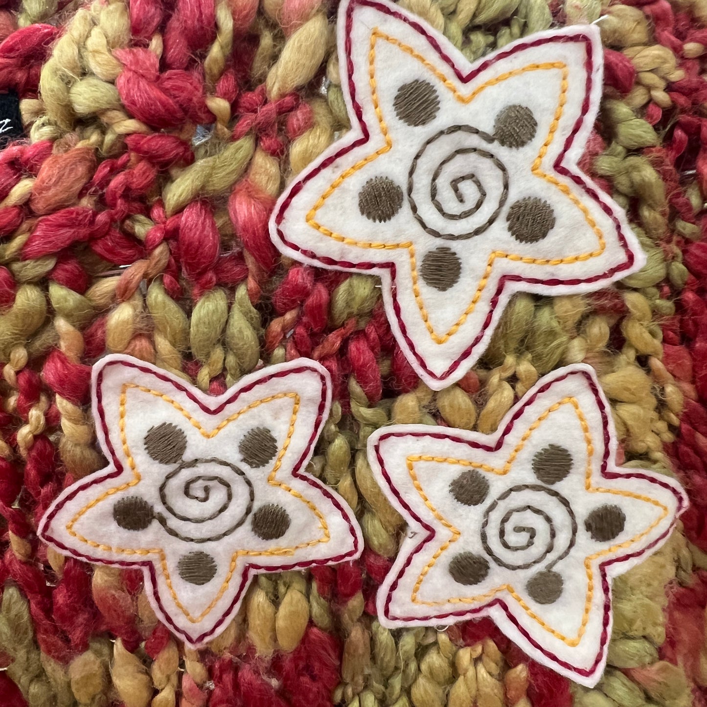 Three embroidered star-shaped patches on a textured fabric background