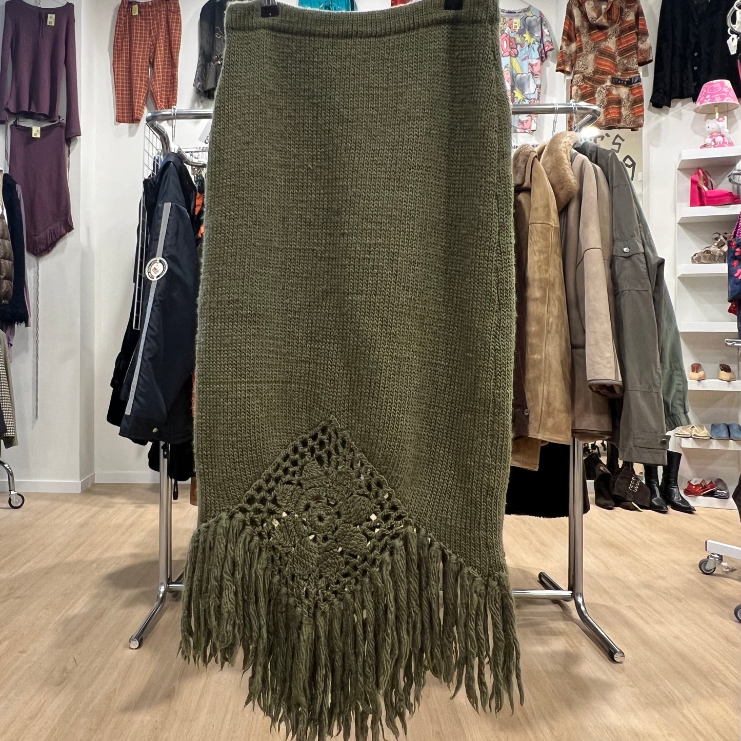 Green knitted skirt with fringe details in a clothing store setting