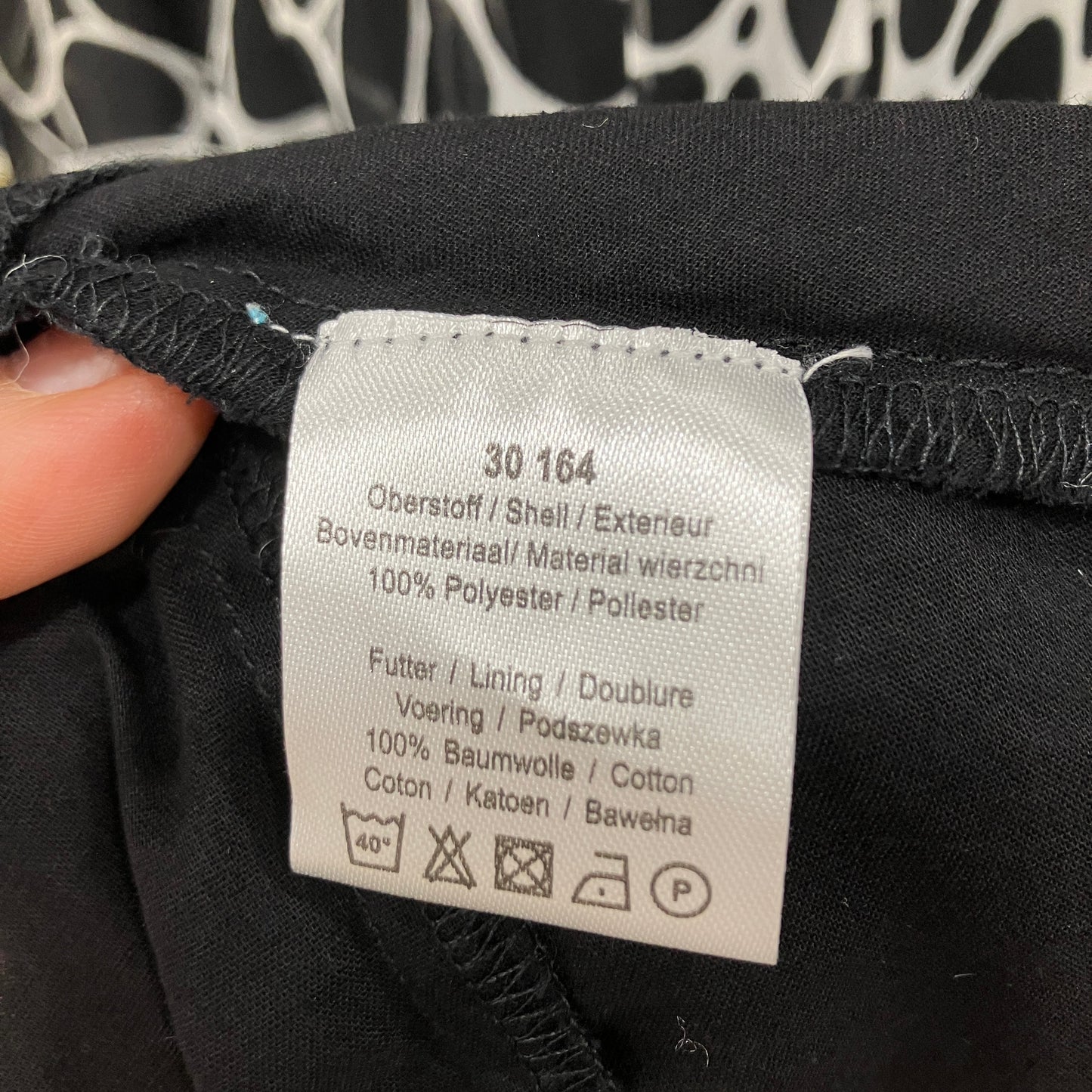 Clothing label on a black garment with text and symbols