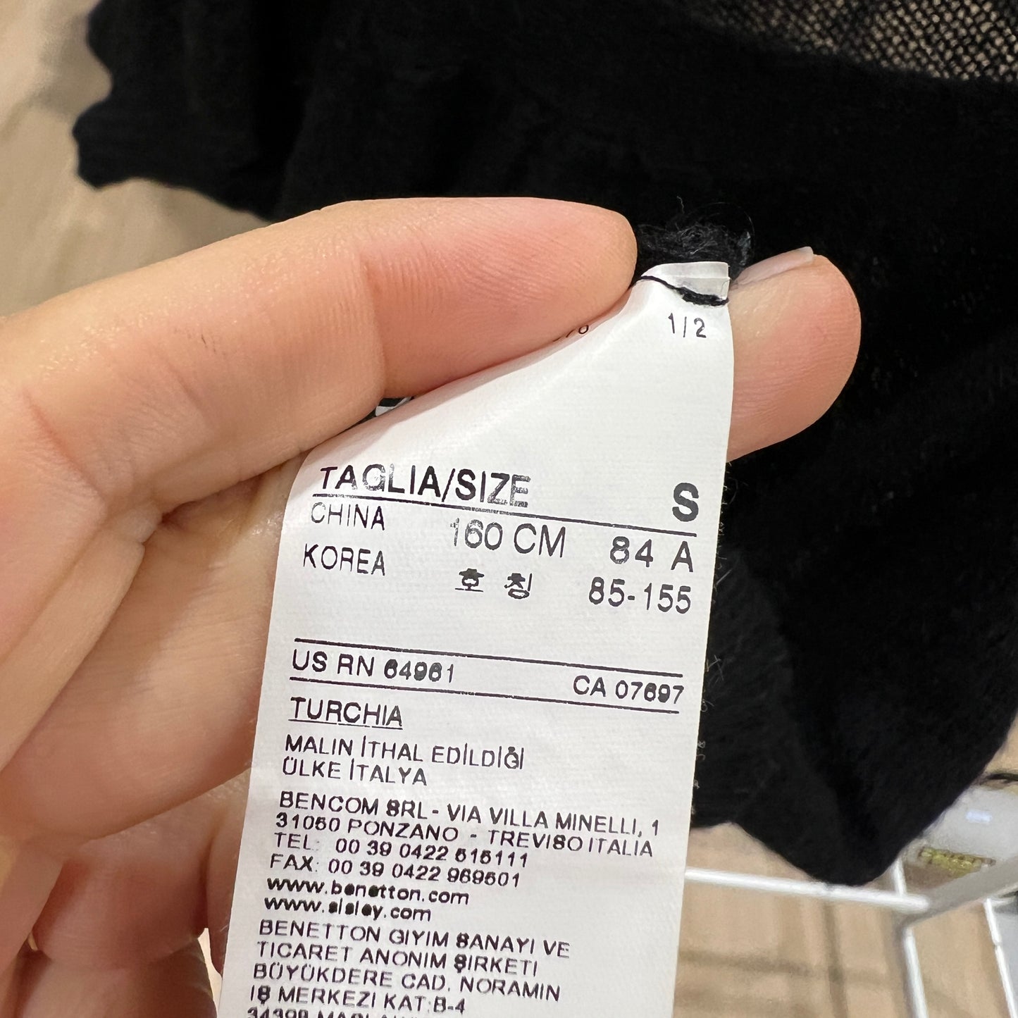 Hand holding a size label with dimensions and country information