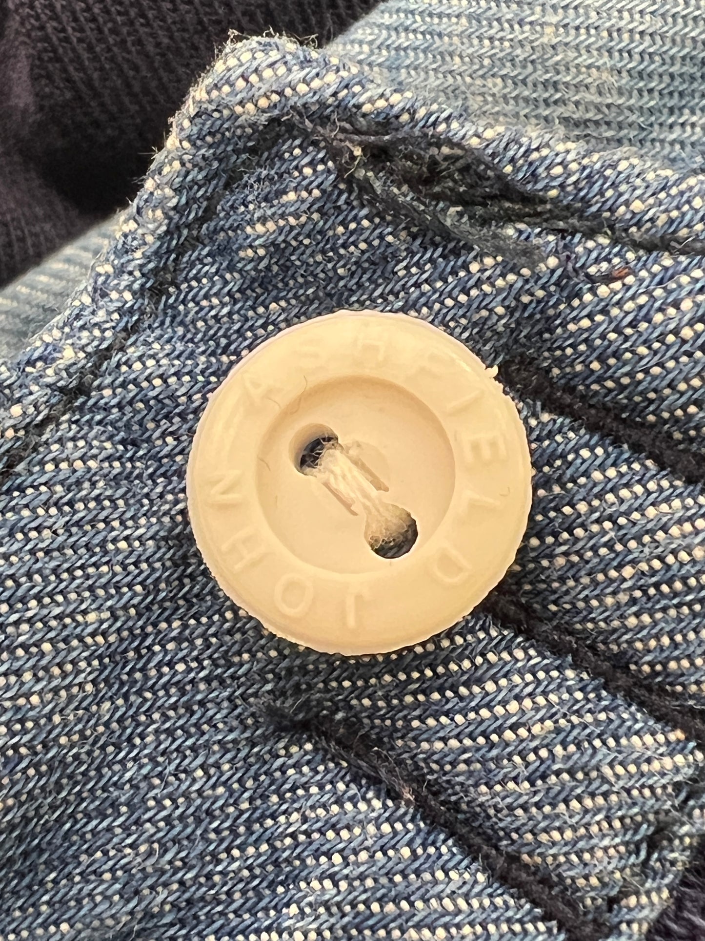 Close-up of a beige button on blue denim fabric