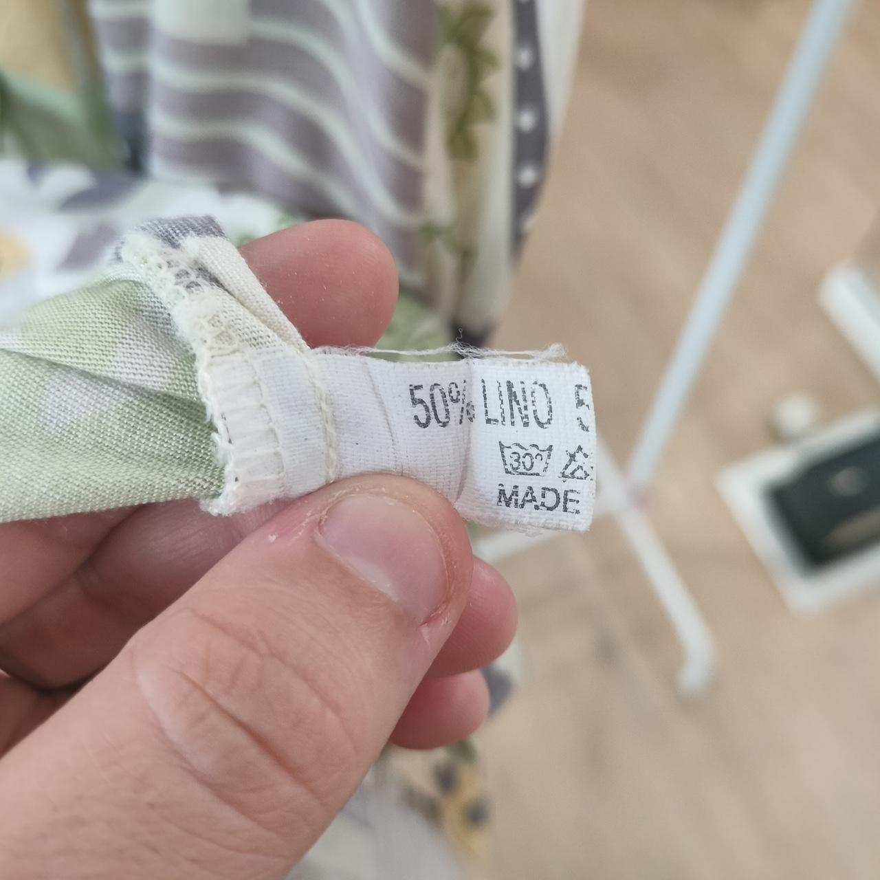 Hand holding a fabric tag with text and symbols, blurred background