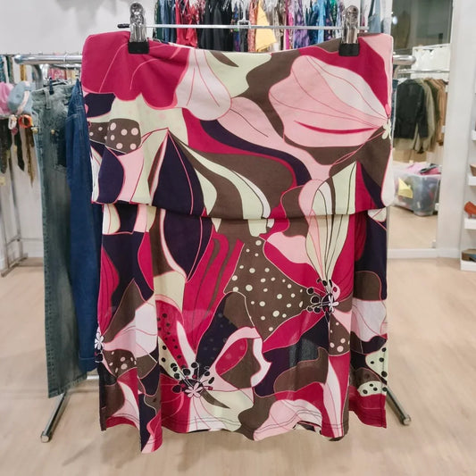 Colorful floral print skirt with red, pink, brown, and cream pattern hanging in store